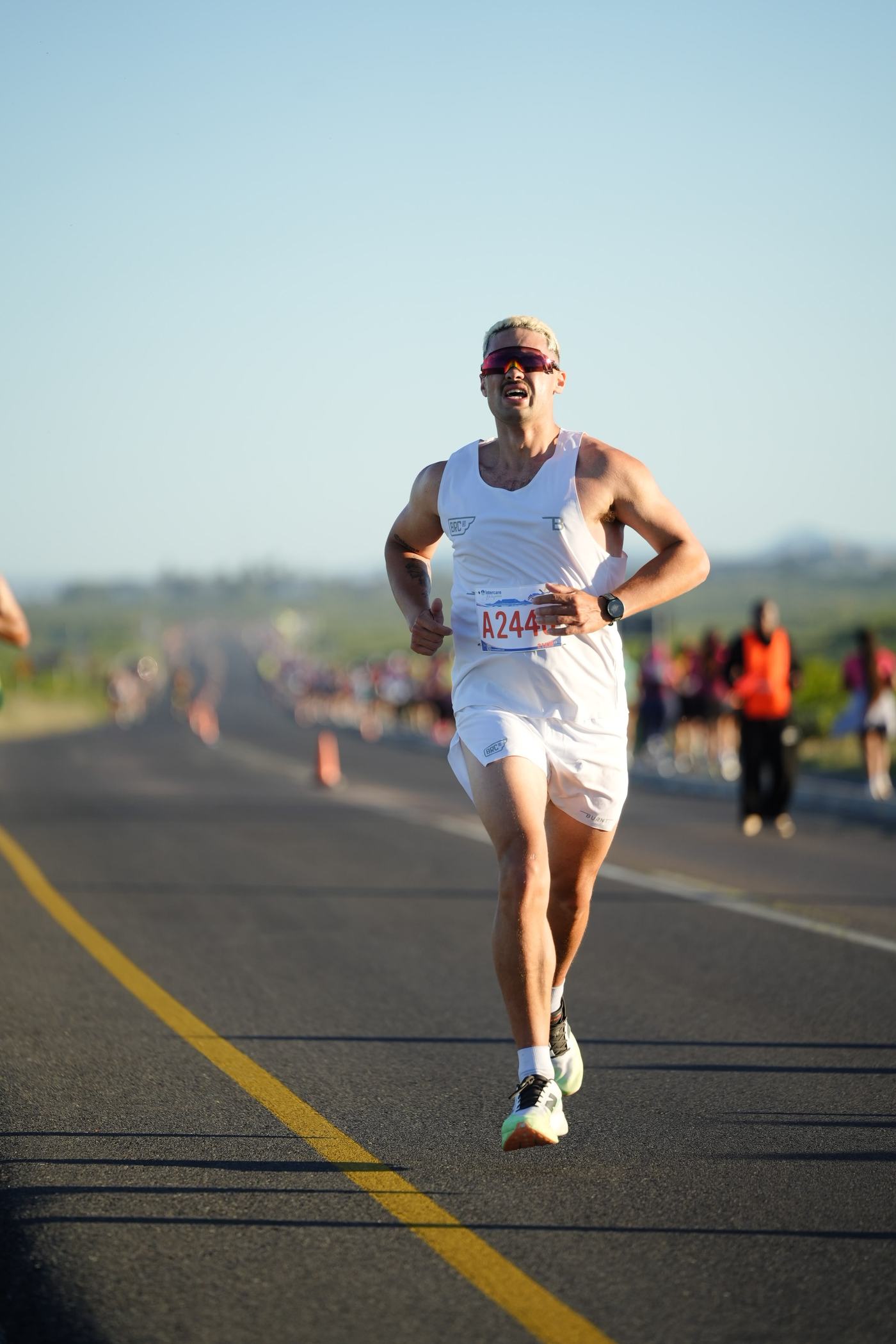 Terrence in a red racing kit, mid-stride on an open road during a race.